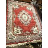 A CHINESE WOOLLEN RUG OF CARPET PROPORTIONS With central floral lozenge and borders on a red field