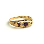 AN EARLY 20TH CENTURY 19CT GOLD, RUBY AND DIAMOND RING Having three round cut graduated rubies,