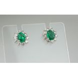 A PAIR OF 18CT WHITE GOLD EMERALD AND DIAMOND DROP EARRINGS Having a single oval cut emerald edged