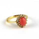 AN 18CT GOLD, CORAL AND DIAMOND RING Having a cabochon cut coral edged with round cut diamonds (size