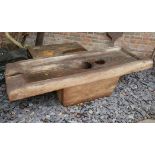 A LARGE INDONESIAN CARVED TEAK RECTANGULAR RICE POUNDING TABLE With concave well to centre. (