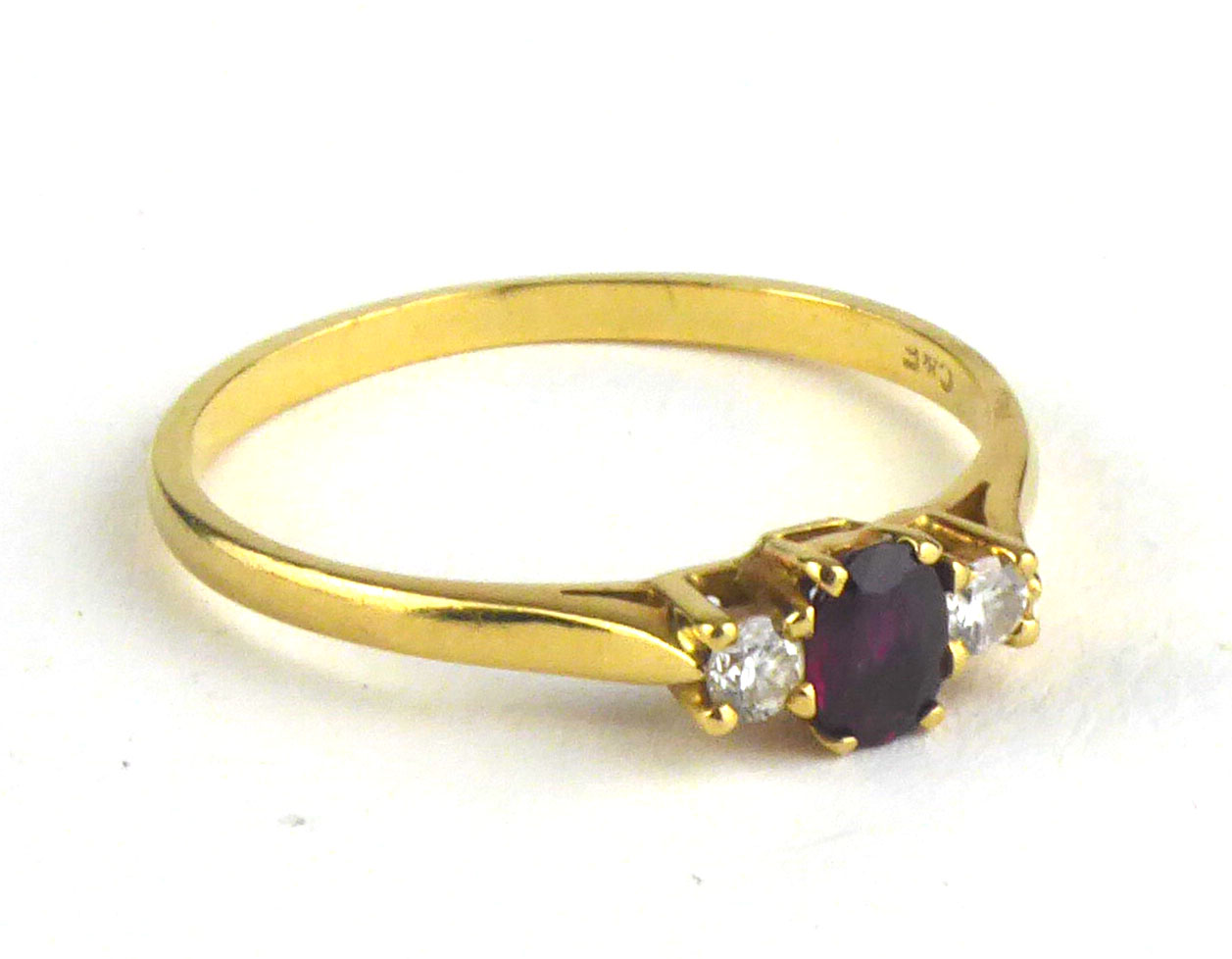 AN 18CT GOLD, RUBY AND DIAMOND THREE STONE RING The central oval cut ruby flanked by diamonds (