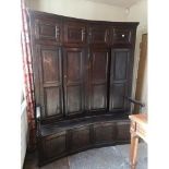 AN ANTIQUE OAK BACON SETTLE The concave back with fielded panelled cupboards above solid seat and