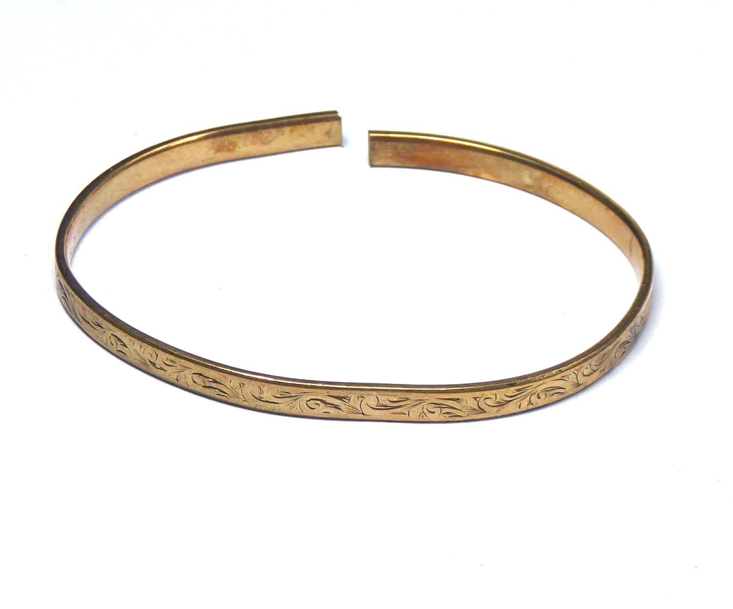 AN EARLY 20TH CENTURY GOLD PLATED SLAVE BANGLE Fine engraved decoration marked 'Metal Core'.