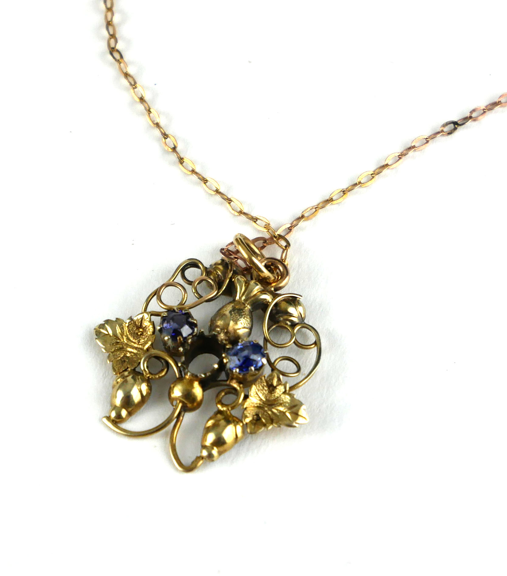 AN ART NOUVEAU YELLOW METAL AND SAPPHIRE PENDANT Having two sapphires in pierced organic form mount,