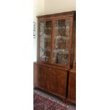 A REGENCY STYLE YEW DISPLAY CABINET With dentil cornice above two glazed doors and cupboards. (113cm