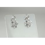 A PAIR OF 18CT GOLD WHITE GOLD AND DIAMOND DAISY CLUSTER DROP EARRINGS The arrangement of round