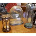 TWO GLASS DOMES WITH BASES Along with a large glass and brass sand timer. (largest 38cm)