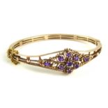 AN EARLY 20TH CENTURY 9CT GOLD AND AMETHYST BANGLE The arrangement of round cut stones forming a