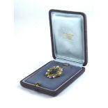 AN EARLY 20TH CENTURY YELLOW METAL EMERALD AND SEED PEARL BROOCH A laurel wreath form with round cut