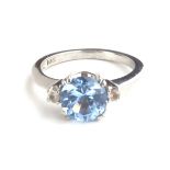 AN AMERICAN 10CT WHITE GOLD AND AQUAMARINE RING Having a single circular stone flanked with white