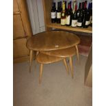 A NEST OF THREE VINTAGE ERCOL ASH AND ELM OCCASIONAL TABLES of kidney form, raised on turned splayed