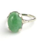 A VINTAGE WHITE METAL AND JADE RING Having a single cabochon cut oval form stone on a plain shank (