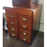 A MID 20TH CENTURY TEAK BANK OF EIGHT DRAWERS Applied with brass cup handles. (60cm x 57cm x 75cm)