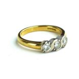 AN 18CT GOLD AND DIAMOND THREE STONE RING Having a row of round cut diamonds in a scrolled mount (