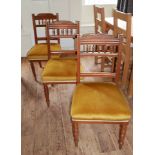 A SET OF SIX EDWARDIAN WALNUT DINING CHAIRS With spindle rails and mustard velvet upholstered seats.