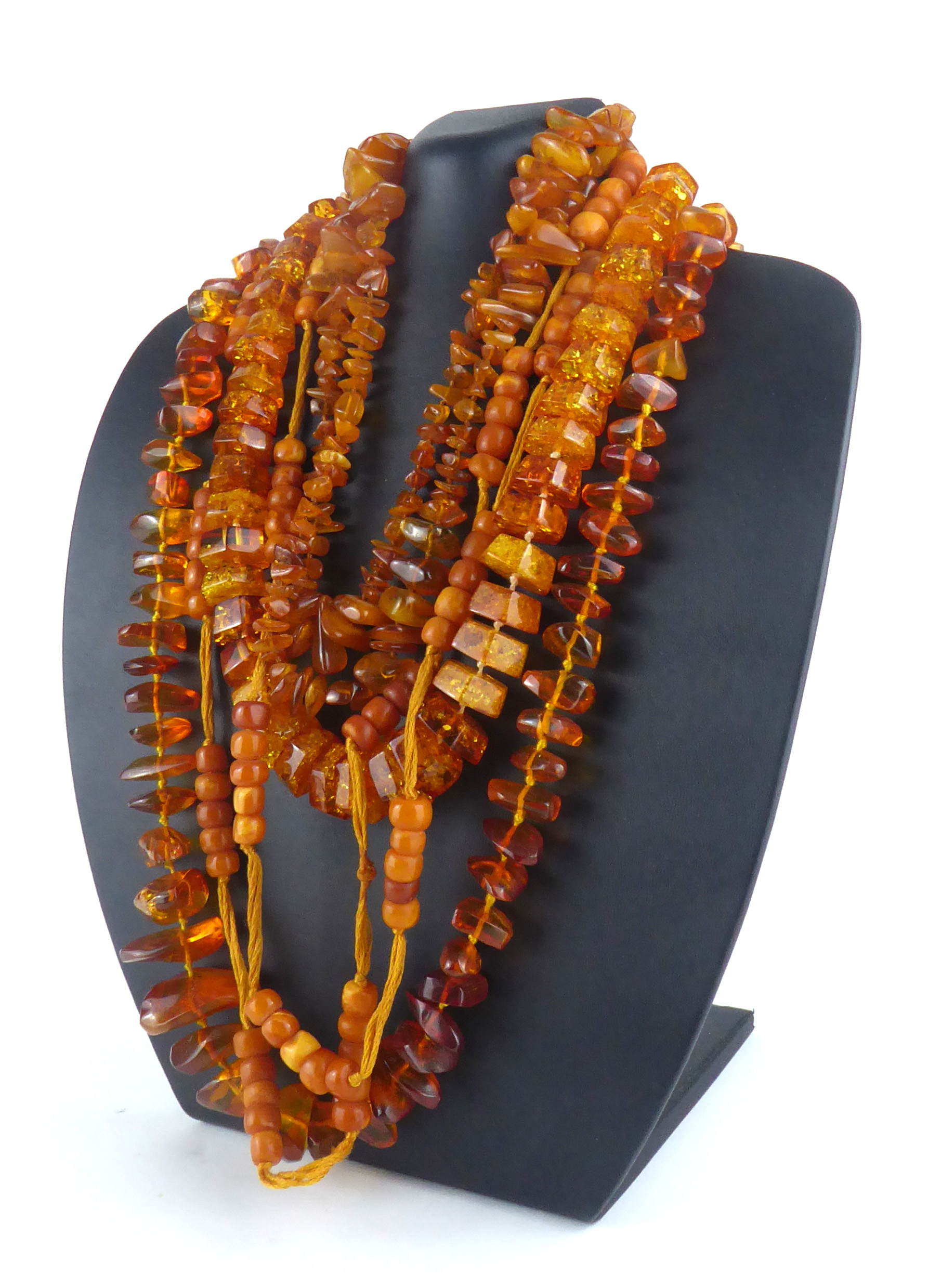 AN EARLY 20TH CENTURY AMBER BEAD NECKLACE Having a cluster of five beads with fabric spaced links,