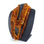 AN EARLY 20TH CENTURY AMBER BEAD NECKLACE Having a cluster of five beads with fabric spaced links,
