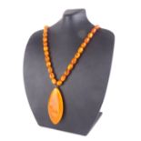 AN EARLY 20TH CENTURY BALTIC AMBER NECKLACE AND PENDANT The single row of oval beads with a