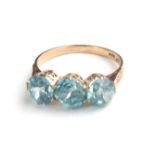 A VINTAGE 14CT GOLD AND BLUE TOPAZ THREE STONE DIAMOND RING Having a row of three round cut