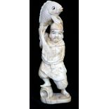 A JAPANESE MEJI PERIOD CARVED IVORY STATUE OF A FISHERMAN Holding a carp aloft, bearing red seal