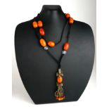 AN EARLY 20TH CENTURY OVAL AMBER BEAD NECKLACE With black fabric strap. (approx total amber weight