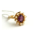 AN 18CT GOLD RING SET WITH AN AMETHYST SURROUNDED BY PEARLS (SIZE N).