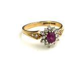 AN EARLY/MID 20TH CENTURY 9CT GOLD RING SET WITH A RUBY SURROUNDED BY DIAMONDS.