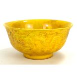 A CHINESE YELLOW GLAZE DRAGON BOWL Having embossed decoration of opposing dragons and six