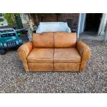 A FRENCH ART DECO TAN LEATHER UPHOLSTERED TWO SEAT SETTEE With dark brown piping, raised on block