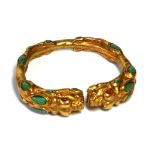 A CHINESE/TIBETAN GILT METAL AND TURQUOISE DRAGON BANGLE Opposing dragons with pear form turquoise
