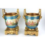 A PAIR OF GILDED BRONZE AND PORCELAIN CACHE POTS Figured with cherub masks and putti. (26cm x