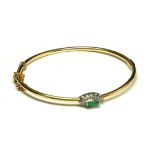 AN 14CT GOLD EMERALD AND DIAMOND BANGLE Having a marquise cut stone, edged with diamonds. (emerald