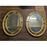 A PAIR OF 20TH CENTURY OVAL GILT FRAME WALL MIRRORS Sectional form with classical urns and