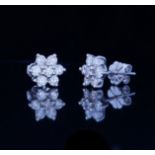 A PAIR OF 18CT WHITE GOLD AND DIAMOND DAISY CLUSTER EARRINGS The arrangement of brilliant round