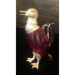 A SILVER PLATE AND RUBY GLASS CARAFE FORMED AS A DUCK With yellow glass eyes. (27cm) Condition: good