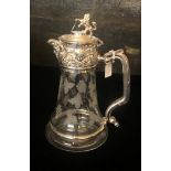 A SILVER PLATE AND ETCHED GLASS CARAFE With lion finial above facial masks, the body decorated