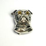 A SILVER NOVELTY PUG DOG BROOCH Having engraved decoration yellow glass eyes. (approx 3cm)