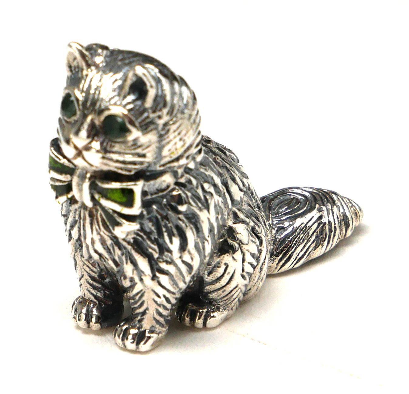 A STERLING SILVER AND ENAMEL NOVELTY 'CAT' FIGURE Seated pose with glass set eyes and enamel bow