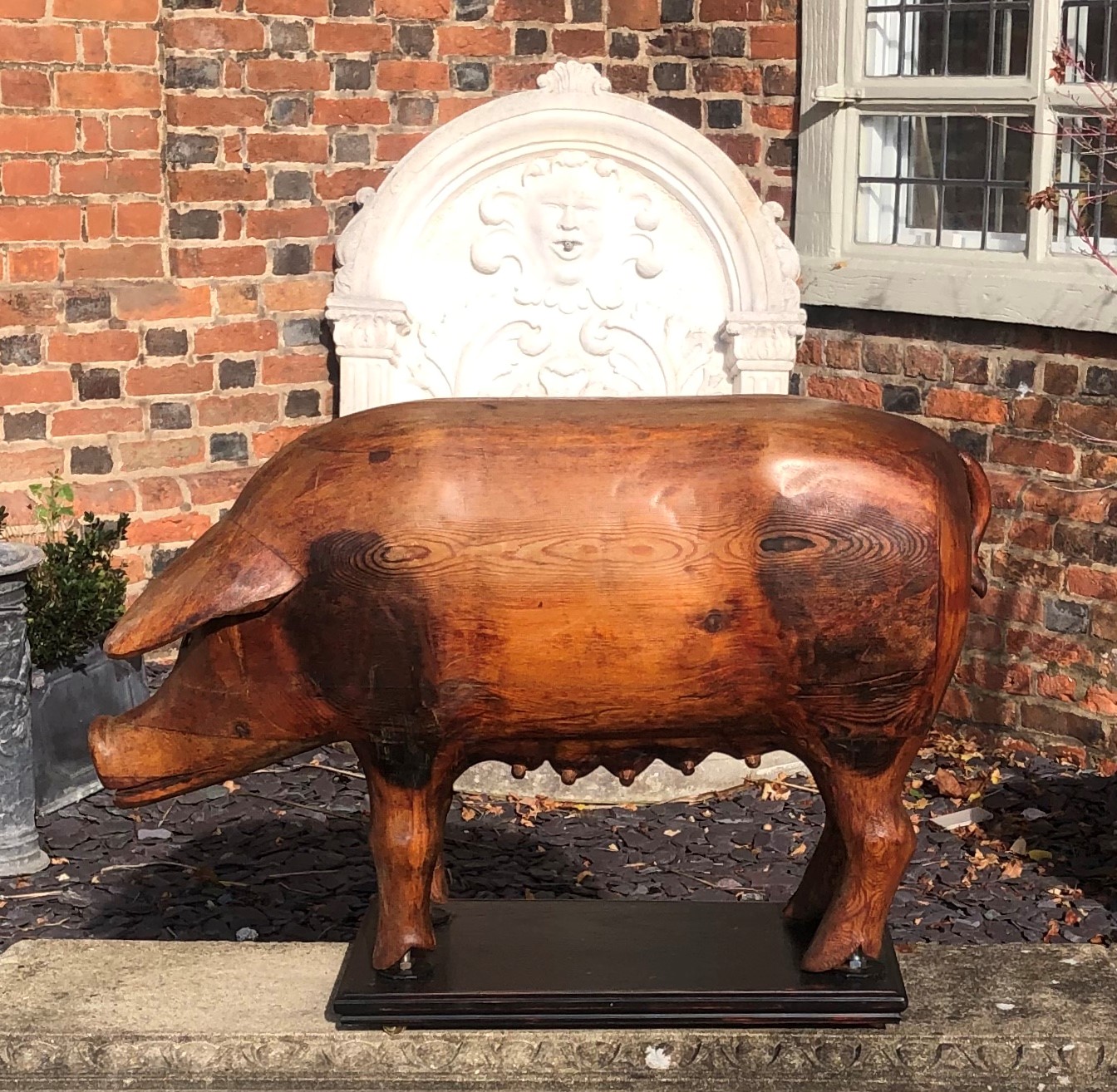 A LARGE CARVED PINE FOLK ART STATUE OF A SOW On later stand. (80cm x 56cm)