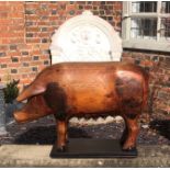 A LARGE CARVED PINE FOLK ART STATUE OF A SOW On later stand. (80cm x 56cm)