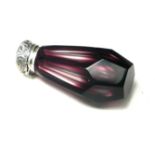 A SILVER AND AMETHYST GLASS SCENT BOTTLE Having an embossed silver top and faceted bottle. (approx
