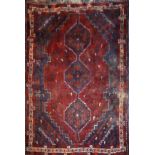 A PERSIAN WOOLLEN RUG Having geometric design to central field on dark red ground with running