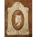 A 19TH CENTURY FRENCH DIEPPE IVORY PICTURE FRAME Heavily applied with coats of arms cherubs