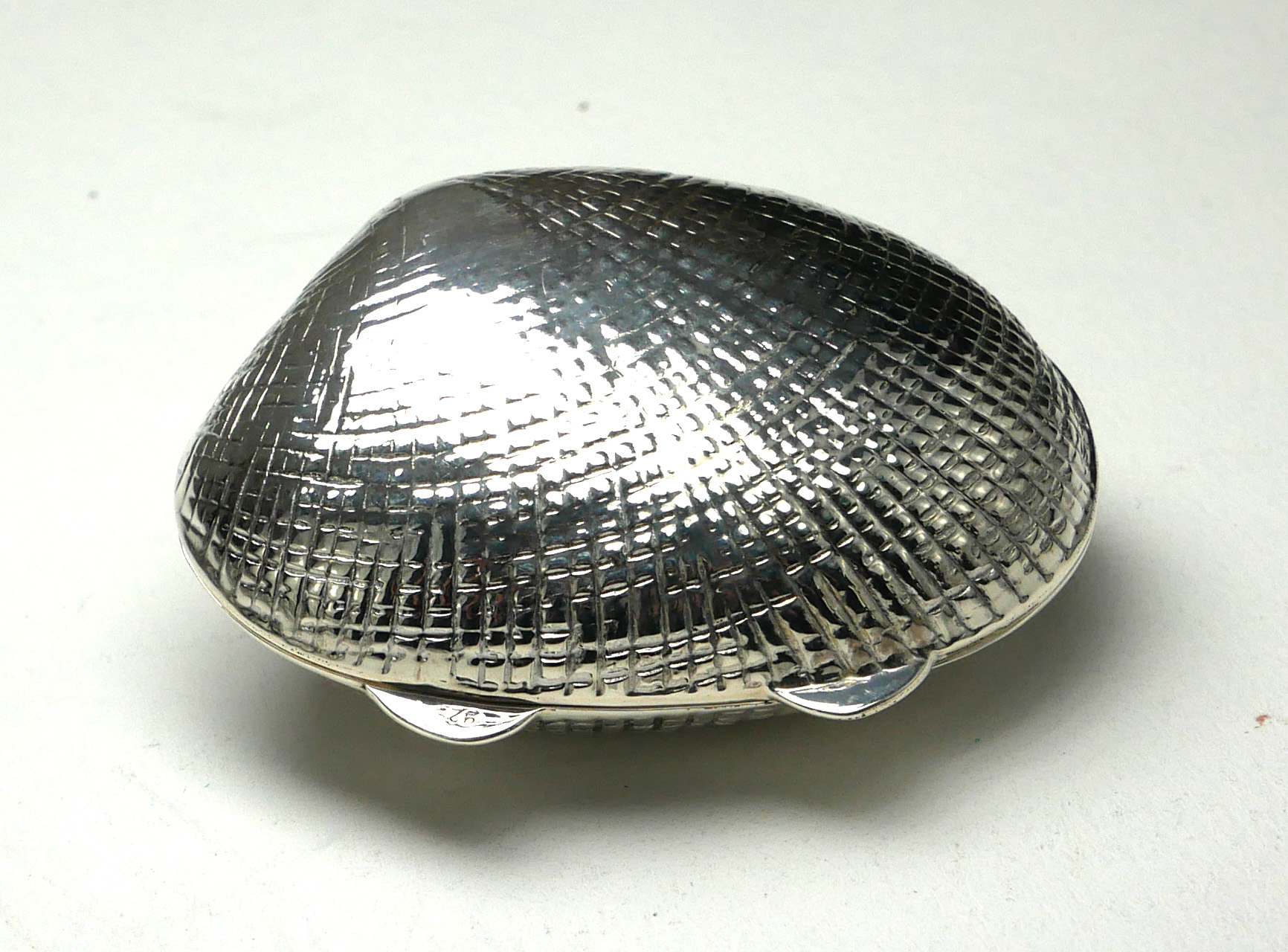 A SILVER 'CLAM SHELL' NOVELTY PILL BOX Having fine textured engraving. (approx 4cm)