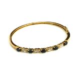 A VINTAGE YELLOW METAL, DIAMOND AND SAPPHIRE BANGLE The arrangement of oval cut stones