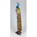 A 21ST CENTURY TAXIDERMY PEACOCK MOUNTED ON A WOODEN PEDESTAL (h 197cm x w 50cm x d 50cm)