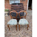A PAIR OF VICTORIAN MAHOGANY BALLOON BACK CHAIRS With carved central rail, overstuffed green