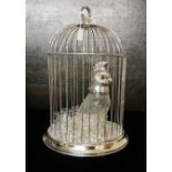 A WHITE METAL BIRDCAGE Containing a drinking set comprising of a parrot carafe with white metal head