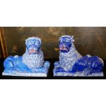 A PAIR OF 19TH CENTURY FRENCH LUNEVILLE FAIENCE POTTERY LIONS Recumbent pose with cobalt blue